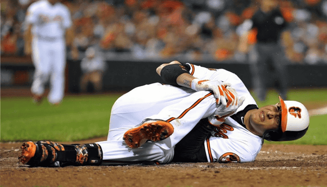 Baseball player lying on the ground clutching his leg