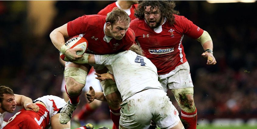 Rugby players in red and white contesting a tackle during a match