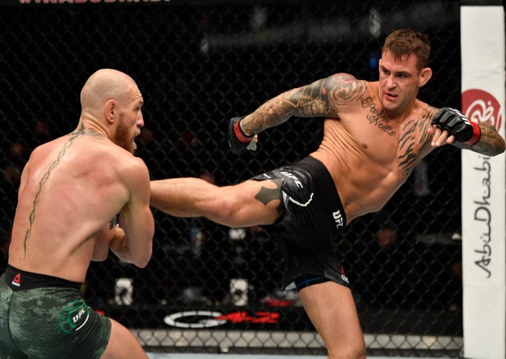 Two mixed martial arts fighters in a cage, one throwing a high kick at the other