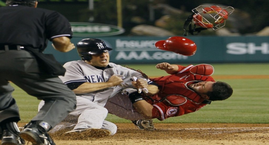 Baseball player sliding into the catcher at home plate