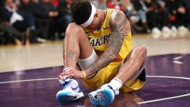 Basketball player sitting on court holding his ankle