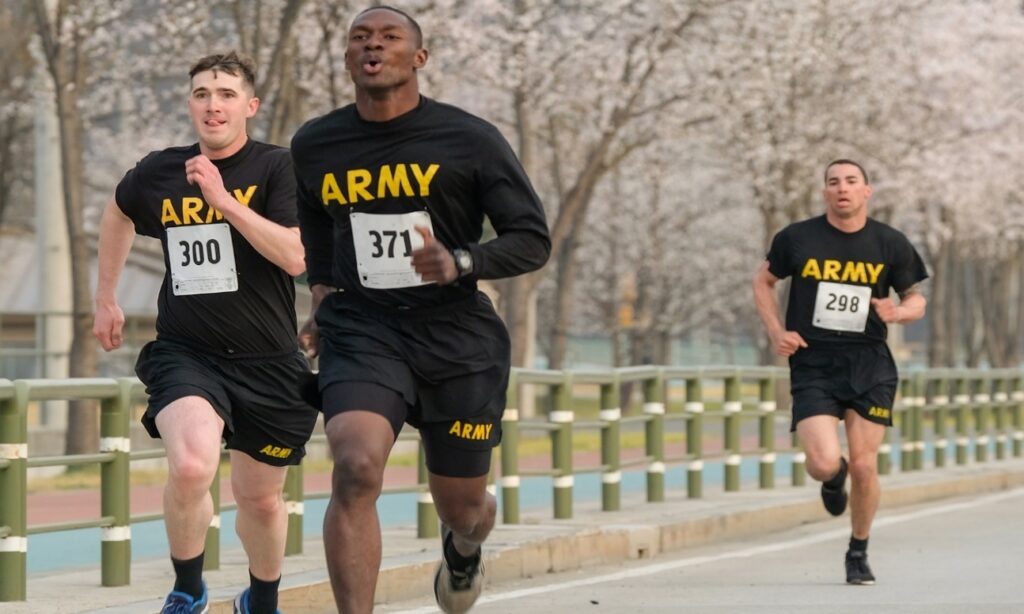 Three runners in army training shirts racing along a road