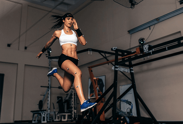 An athlete wearing motion-capture markers in mid-leap in a biomechanics lab