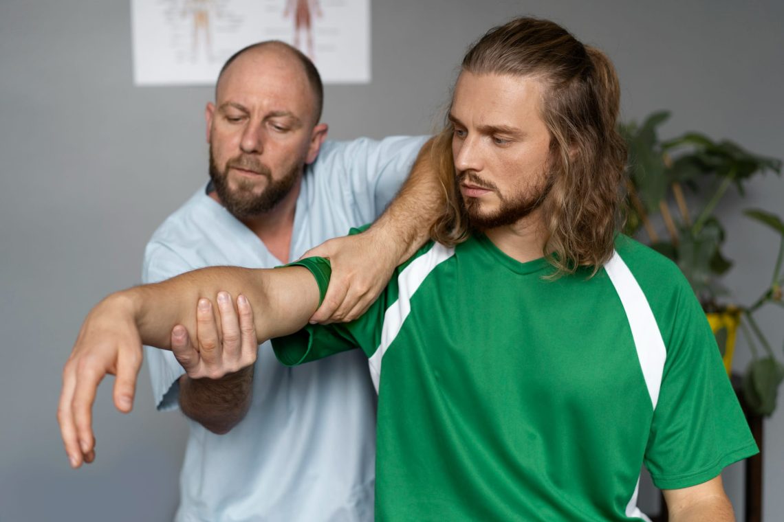A therapist assessing a footballer's shoulder range of movement in a clinic room.
