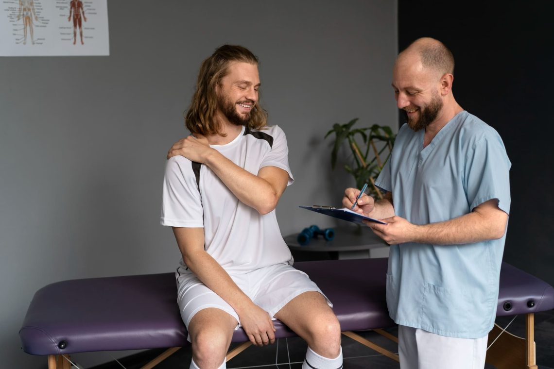 A clinician taking notes while assessing a seated patient's shoulder.