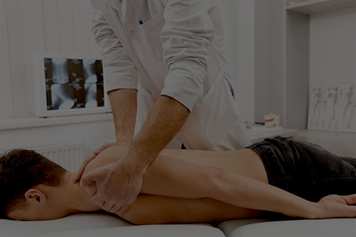 A chiropractor treating a patient lying face down on a treatment couch in a clinic room.
